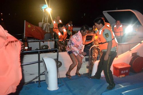 Local officers help a fisherman escape from a fishing boat which is on fire in the sea area of Dongchongkou in Ningde, East China's Fujian Province, July 30, 2012. Seven fishermen in the boat were rescued. One of them suffering from severe fire burn was sent to hospital. Photo: Xinhua