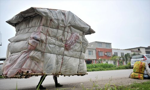 Liu Lingchao carries his portable house at the Liucheng county section of the G209 national highway in Liuzhou, Guangxi Zhuang Autonomous Region, on Wednesday. Liu, 38, from Longcheng village of Rongan county, Guangxi, left Shenzhen, Guangdong Province, five years ago to walk to his hometown, and has walked roughly 1,000 kilometers. He refused other people's help and earns money by collecting plastic bottles and other waste materials. Photo: CFP