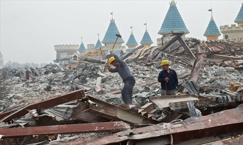 Workers hammer the debris of the Wonderland Amusement Park in Beijing's Changping district. The park, with the ambition of becoming Asia's largest fairground, has stayed idle since 1998 due to shifting land policies. Local officials said the site would be transformed into an outlet mall. Photo: CFP
