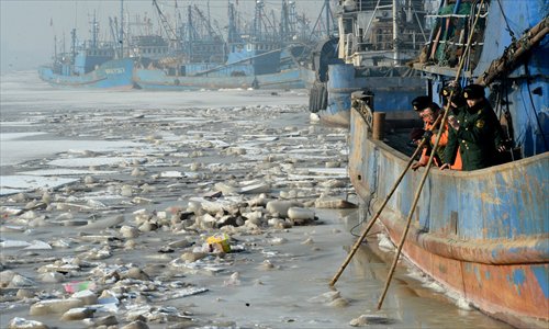 Policemen help local fishermen break ice in waters near Cangzhou, Hebei Province, Sunday. As temperatures plunged, the Bohai Sea saw coastal waters near Cangzhou freeze over the weekend, trapping many fishing boats. Photo: CFP