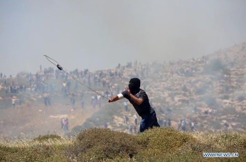 A Palestinian protester hurls stones at Israeli soldiers during clashes after a protest against settlement's expansion and settlers attack in the west bank village of Dir Jrer near Ramallah on April 26, 2013. Six protesters were injured during clashes between Palestinians and Israeli soldiers. (Xinhua/Fadi Arouri) 