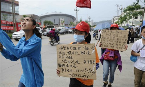 Quake-relief volunteers hold signs in hopes of recruiting more volunteers to help victims in hard-hit areas on a street in Lushan April 25. Photo: Li Hao/GT