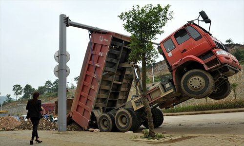 A truck driver was unharmed after his vehicle caught a traffic light, hoisting him about a meter above the ground in Guizhou Province on Sunday. 
He will pay the damages and a fine for illegally dumping  construction waste on the street before the accident. 
Photo: CFP