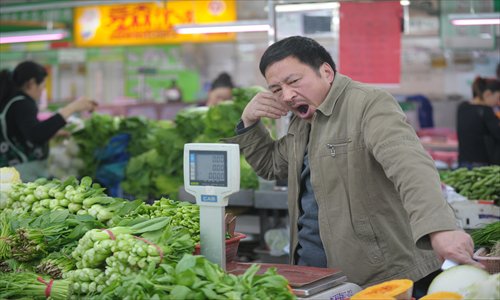 A vegetable seller waits for customers in a wet market in Shanghai on Sunday. China's economic growth slowed to 7.7 percent in the first quarter, data showed, below expectations. Photo: AFP