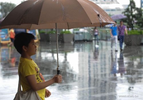 A boy holds an umbrella amid rain in Shenzhen, south China's Guangdong Province, May 26, 2013. Torrential rain hit most parts of Guangdong Province from Saturday to Sunday. (Xinhua/Mao Siqian)&nbsp; 