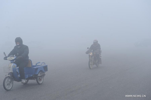 People ride on a street in dense fog in Baoding, north China's Hebei Province, Jan. 12, 2013. Heavy fog hit many parts of Hebei Province on Saturday. The visibility was less than 200 meters in some areas. (Xinhua/Zhu Xudong)