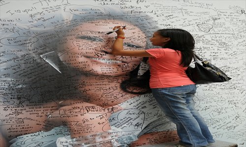 A fan of US pop diva, Whitney Houston, signs a giant mural with a portrait of her idol displayed at a mall in Manila, the Philippines, on Friday, as a tribute to the pop legend who died on February 11, aged 48 in a Beverly Hills hotel. Photo: AFP