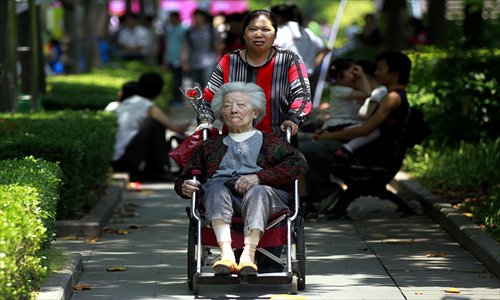 An elderly lady in a wheelchair buys a carnation at Xujiahui Park in downtown Shanghai on Mother's Day, which fell Sunday, when some 110,000 carnations were scattered around in a city-wide charity sale. Photo: Yang Hui/GT