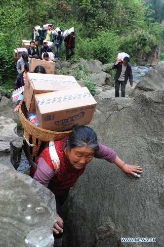 Villagers carrying disaster relief supplies walk in the mountain in quake-hit Shifeng Village of Lushan County, southwest China's Sichuan Province, April 22, 2013. The road linking the Shifeng Village with the outside had been destroyed by a 7.0-magnitude earthquake on April 20. Local villagers set up a 300-member group to climb mountains to get relief supplies outside and then return to the village. Over 40 tonnes of materials had been transported and distributed to over 2,000 villagers. (Xinhua/Li Ziheng) 