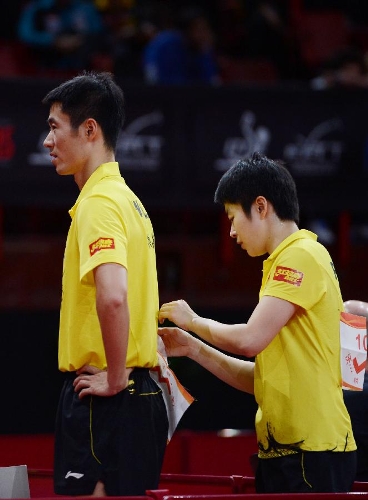 Rao Jingwen (R) of China helps her partner Wang Liqin take off his number bib after the first round of mixed doubles against Thavisack Phathaphone and Thiphakone Southammavong of Laos at Palais omnisport de Paris Bercy in Paris, France, on May 14, 2013. Wang and Rao won 4-0. (Xinhua/Tao Xiyi) 