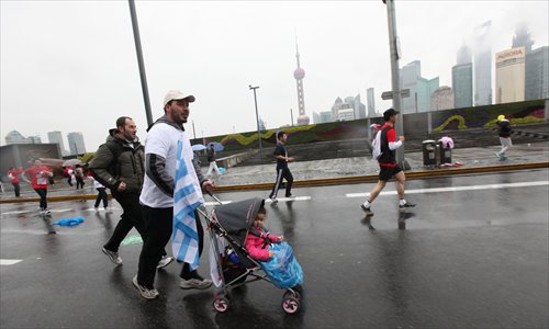 A runner pushes a child in a stroller during the annual Shanghai International Marathon on December 2. More than 30,000 runners participated in the annual Shanghai International Marathon Sunday, the most in the marathon’s 17-year history, according to organizers. Photo: Cai Xianmin/GT


