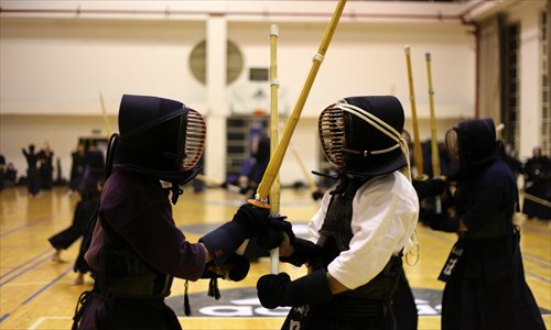Wearing black armor and helmets, barefooted kendo practitioners engage each other in a stadium in downtown Shanghai. Photo: Cai Xianmin/GT