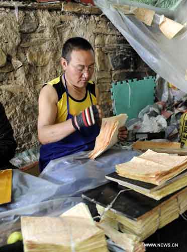 A monk rearranges sutra in the Dra Yerpa temple built on a hillside in Dagze county of Southwest China's Tibet Autonomous Region, September 9, 2012. The temple is notable for its meditation cave connected with Songtsen Gampo, the 7th century Tibetan king. Photo: Xinhua