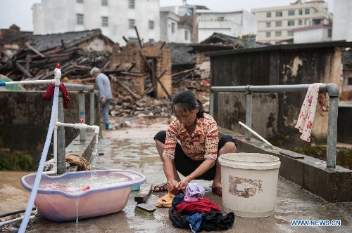 A villager washes clothes in front of houses destroyed by the rainstorm in Guangfu Town of Jiaoling County, Meizhou City, south China's Guangdong Province, May 22, 2013. Meizhou City was hit by a rainstorm on May 19, which killed one people and destroyed 951 houses, leaving 180, 000 people affected in Jiaoling County. (Xinhua/Mao Siqian)&nbsp; 