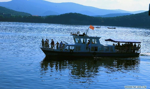 Visitors enjoy the scenery of the Jingpo Lake on a boat in Mudanjiang, northeast China's Heilongjiang Province, July 7, 2012. About 30 percent more tourists have visited the Jingpo Lake scenic area this year than the same period last year, following a series of promotions. Photo: Xinhua