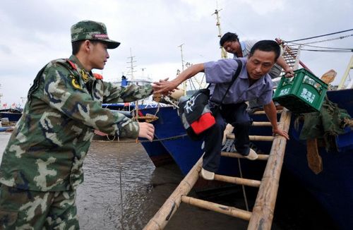 A soldier helps fishermen to disembark from a boat in Shitang Port, Wenling city, East China's Zhejiang Province, September 15, 2012. According to forecast by the Zhejiang Meteorological Center, typhoon Sanba, the 16th typhoon seen this year, approaches waters of the eastern part of the East China Sea on Saturday. Residents of the country's coastal regions were urged be well-prepared for possible typhoon effects and take precautions against wind, moisture and strong rainfall. Photo: Xinhua