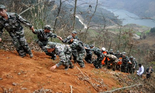 Rescuers drag the injured and corpses up along a mountain slope after a traffic accident in Congjiang county, Southwest China's Guizhou Province on Saturday.  Thirteen people were killed and 21 were injured in the accident. An initial investigation showed that the coach designed for 19 passengers was carrying 34 when the accident occurred. A further investigation into the cause of the accident is underway. Photo: IC