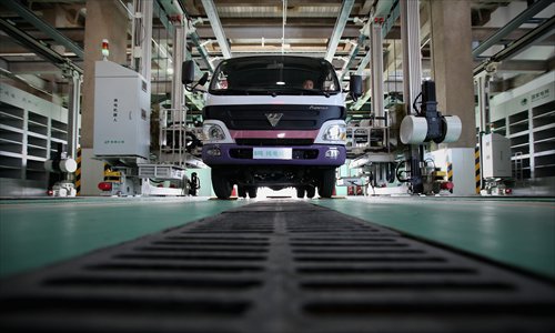 A truck driver watches as a battery-exchange robot switches out the batteries in his vehicle at China's largest electric vehicle battery recharging station in Beijing on May 30. Photo: CFP