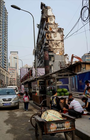 The facade of an 8-storey building which is being dismantled in Guiyang, Guizhou Province looms precariously over the street on Wednesday. The building, although wrapped up in tarpaulin, is described by local residents as 