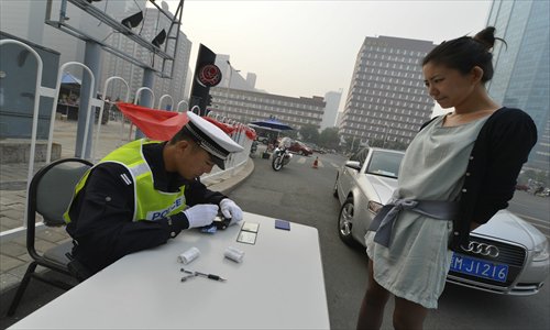 A woman is stopped by police after breaking the city's anti-congestion rules at Yonganli, Chaoyang district, Monday. Many drivers were caught after the policy was suspended over the October holidays. Photo: CFP