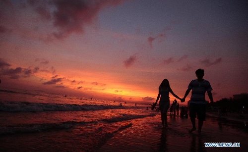 People enjoy themselves on a beach at sunset in Sanya, south China's Hainan Province, May 16, 2013. (Xinhua/Chen Wenwu)&nbsp; 