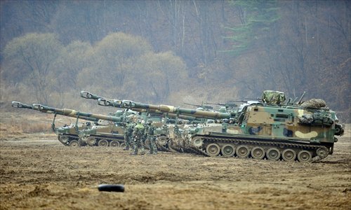 South Korean soldiers wearing gas masks stand in front of K-55 self-propelled howitzers at a military training field on the border city of Paju on Tuesday. Photo: AFP