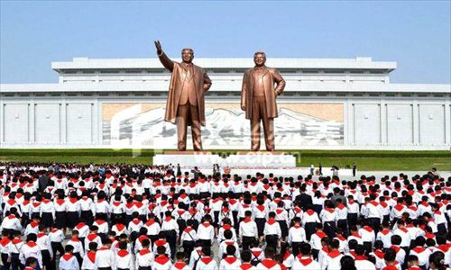Children offering flowers to the statues of Kim Jong-il and Kim Il-sung