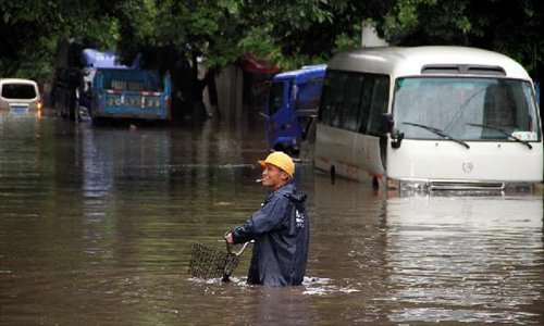 A rider pushes his bike in flood water in Guilin City, southwest China's Guangxi Zhuang Autonomous Region, April 30, 2013. Heavy rainfall hit Guangxi on April 29, making house damaged and causing floods and road cave-ins as well. (Xinhua/Ren Jiaxiang)