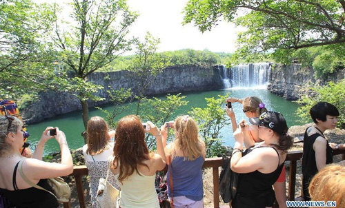 Russian visitors take photos of the Diaoshuilou Waterfall at the Jingpo Lake scenic area in Mudanjiang, northeast China's Heilongjiang Province, July 7, 2012. About 30 percent more tourists have visited the Jingpo Lake scenic area this year than the same period last year, following a series of promotions. Photo: Xinhua