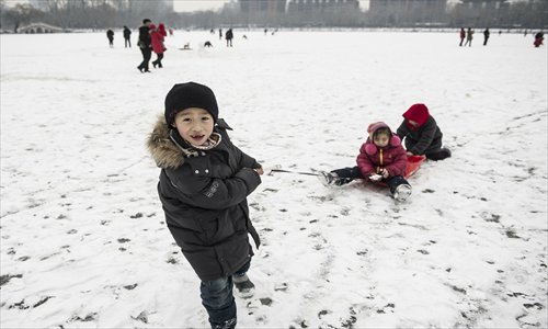 Children play on a sled at Yuyuantan Park in the snow Sunday in relatively fresh air. The snow helped to bring down pollution levels in the capital, after PM2.5 levels rose to over 500 again Friday. Photo: Li Hao/GT