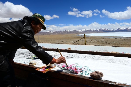 &nbsp; Painter Mo Huasheng draws a painting near the icy lake Nam Co located at the boundary of Damxung and Baingoin counties, southwest China's Tibet Autonomous Region, on May 12, 2013. Lake Nam Co, the highest saltwater lake of the world at 4,718 meters above the sea level, is regarded as a sacred lake in Tibetan Buddhism. (Xinhua/Chen Tianhu)