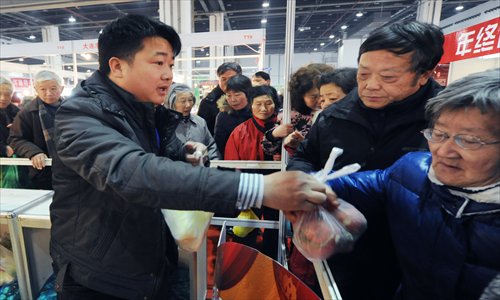Local resident Wu Zehai gives out free fresh vegetables at an agriculture fair that opened Wednesday at the Everbright Convention and Exhibition Center. Wu, who came to Shanghai 10 years ago, wanted to express his gratitude to the city. Photo: CFP