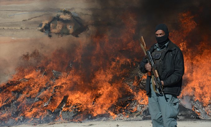An Afghan policeman stands guard as a pile of narcotics is burned by officials on the outskirts of Jalalabad Nangarhar province on Wednesday. The United Nations said in November that opium poppy cultivation in Afghanistan has increased by 18 percent this year, sending a 