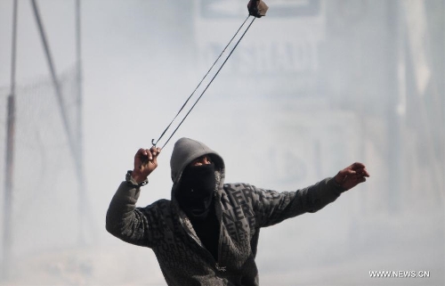 A Palestinian youth hurls stones toward Israeli soldiers during clashes in the West Bank village of al-Khader near city of Bethlehem, April 5, 2013. (Xinhua/Luay Sababa) 
