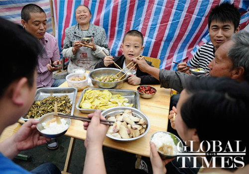 Victims eat in a makeshift shelter set up on the playground of the Lingguan Middle School on Sunday. Photo: Li Hao/GT