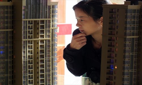 A woman looks at a housing model in Yichang, Hubei Province Thursday. Investments in real estate development totaled 5.1 trillion yuan ($816 billion) in the first nine months of this year, growing 13.8 percent year-on-year after deducting pricing factors, the National Bureau of Statistics said Thursday. Photo: CFP
