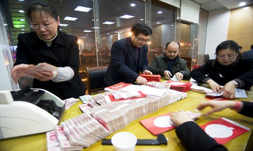 Employees at a China Construction Bank branch work overtime Tuesday in Haian, Jiangsu Province, to count and prepare the cash local construction companies will need to pay migrant workers their salaries and annual bonuses before the upcoming Chinese New Year. Photo: CFP