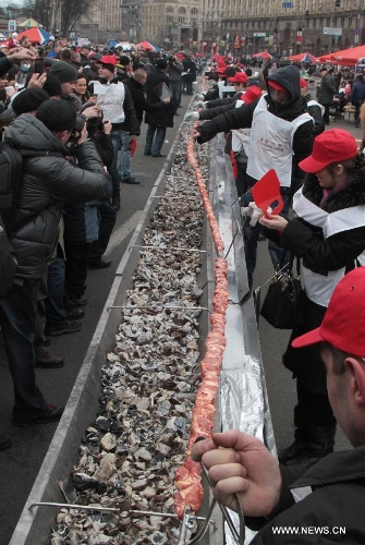 People grill a long shish kebab in Kiev, Ukraine, March 2, 2013. A 150.6-meter-long kebab was made in Kiev on Saturday. A total of 200 kg of meat and 800 kg of charcoal were used to make the kebab.(Xinhua/Sergey Starostenko) 