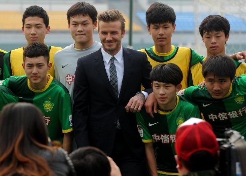 British soccer player David Beckham (C) poses with juvenile footballers of Beijing Guo'an Soccer Club in Beijing, capital of China, on March 21, 2013. Beckham visited the club as the ambassador for the youth football program in China and the Chinese Super League Thursday. (Xinhua/Gong Lei) 