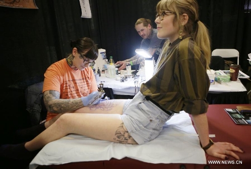 A tattoo artist works on her client's body during the 5th Vancouver tattoo and culture show in Vancouver, Canada, on April 26, 2013. The 5th Vancouver tattoo and culture show presents different tattoo art works from nearly 200 tattoo artists from across the world attracting thousands of tattoo lovers here on Friday. (Xinhua/Liang Sen) 