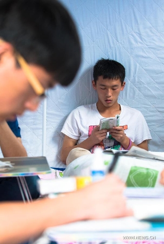Li Jiajun, a high school student, studies to prepare the college entrance exam this summer in a tent at a temporary settlement at the Tianquan Middle School in quake-hit Tianquan County, Ya'an City, southwest China's Sichuan Province, April 22, 2013. A 7.0-magnitude earthquake jolted Lushan County of Ya'an City in the morning on April 20. (Xinhua/Liu Jinhai)