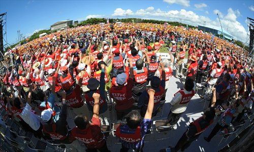 People raise their arms during a rally denouncing the deployment of Osprey military transport aircraft by the US in Ginowan, Okinawa prefecture in Japan, on Sunday over safety concerns following reports on recent crashes. A dozen MV-22 Ospreys are scheduled to be deployed at the US Marine Corps air station in Okinawa in October, despite a series of accidents involving the hybrid transport aircraft. Photo: AFP 