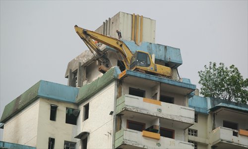An excavator  is seen on  top of a building  more than 10 floors high in Chongqing on Tuesday. The excavator was hoisted onto the building to demolish it from the top. Photo: CFP