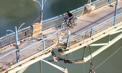 A rebel fighter and a child cross a damaged bridge in Syria's Deir Ezzor on Monday. US President Barack Obama launched an intense lobbying effort on Sunday to sway skeptical lawmakers weighing up whether to support a military strike against Syria. Photo: AFP