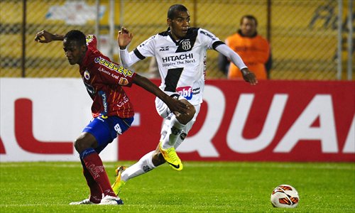 Regis (right) of Ponte Preta from Brazil takes  the ball past Jerry Mina of Deportivo Pasto from Colombia during their 2013 Copa Sudamericana match at Libertad Stadium in Pasto, Colombia on Tuesday. Deportivo Pasto won 1-0. The event is South America's secondary international club soccer tournament, inferior to the Copa Libertadores. Photo: AFP