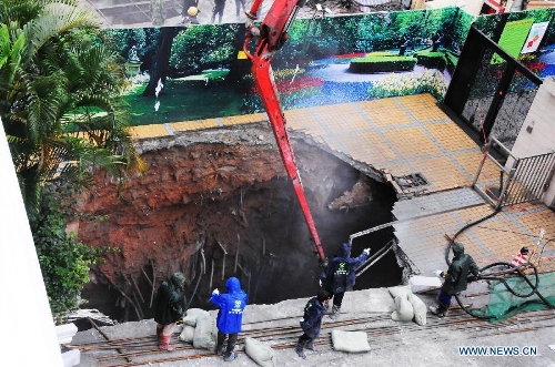 Workers conduct work at a land subsidence accident spot in a community in Futian District of Shenzhen, south China's Guangdong Province, March 27, 2013. A security guard working at the community, who happened to walk past the subsidence area, fell and died. More than 400 families in the community were cut off from water supply due to the accident. (Xinhua/Tian Jianchuan)
