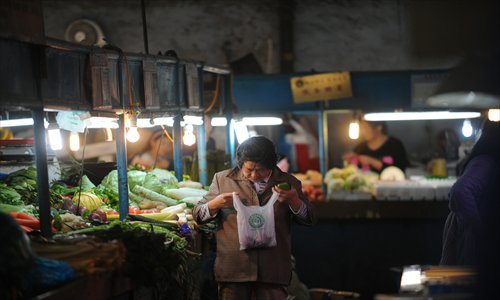 An elderly woman looks at vegetables she just bought in a market in Shanghai on Thursday. Photo: AFP
