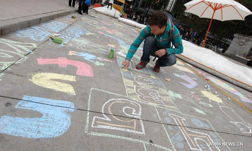 A man chalk-draws on the pavement during first Chalkupy Vancouver event in Vancouver, Canada, on September 22, 2012. People from all walks of life descend on Robson Street in downtown Vancouver at noon to create beautiful sidewalk chalk art together. Photo: Xinhua