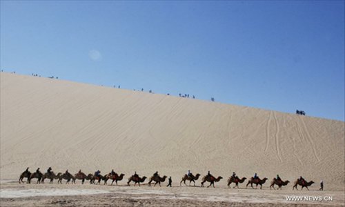 Tourists ride camels at the scenic spot of Crescent Lake in Dunhuang City, northwest China's Gansu Province, October 4, 2012. Dunhuang, a major stop on the ancient Silk road well known for its Mogao Caves (Caves of 1,000 Buddhas), Crescent Lake and Mingsha Mountain, has attracted large numbers of tourists from both home and abroad during the National Day holiday. Photo: Xinhua