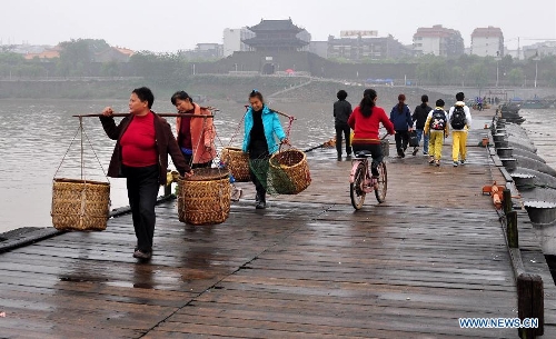 People walk on an ancient floating bridge across the Gongjiang River in Ganzhou, east China's Jiangxi Province, April 1, 2013. The wooden bridge, running 400 meters, is supported by some 100 floating boats anchored in a row. The bridge could date back to the time between 1163 and 1173 during the Song Dynasty, and has become a scene spot of the city. (Xinhua) 